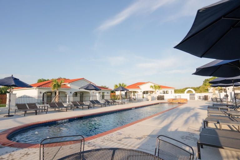 a pool with chairs and umbrellas. resort pool